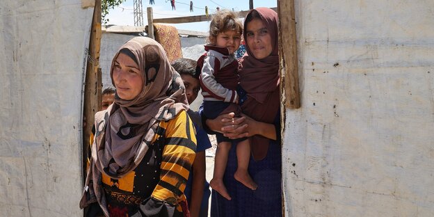 Eine syrische Flüchtlingsfamilie schaut aus dem Eingang einer Zeltstadt heraus